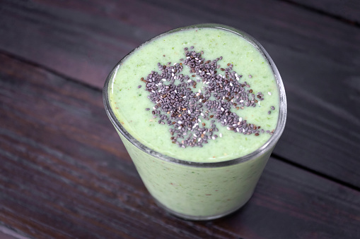 Healthy green kale smoothie greek yogurt with chia seeds in glass on wooden table background, top view. Superfood of drink a great source of vitamins and minerals.