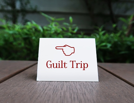 Direction sign on paper note GUILT TRIP,means to manipulate or cause another person to feel guilt sense of responsibility and change behavior