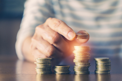 Senior woman hand add more coin on pile of coins for fund, SSF, LTF, RTF, savings, retirement, pension, life insurance concept