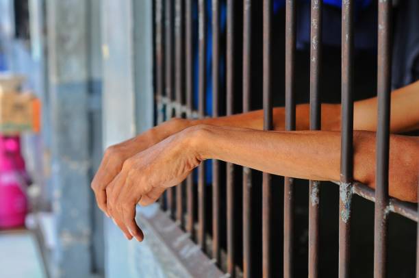 hands of a prisoner behind prison bars