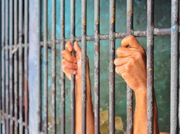 istock hands of a prisoner behind prison bars 1904254417