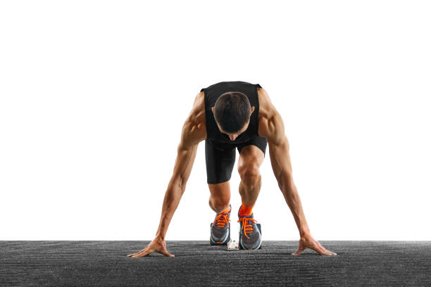 Young athletic sportsman, professional runner trains running from low start against white studio background. Concept of sport, active lifestyle, action, victory, workout. Copy space. Ad