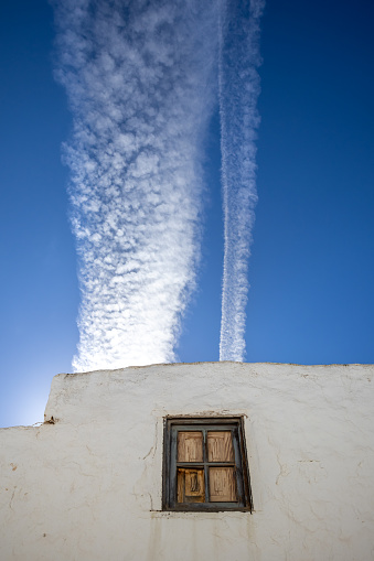 Deetails of the traditional spanish architecture with a white facade. Bright blue sky with contrast white chemtrails. Teguise, Lanzarote, Canary Islands, Spain.
