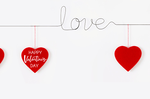 Valentine's Day concept with word love made with wire and felt hearts with message on white background