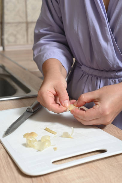 istock Woman in the kitchen cleans and cuts pickled garlic on a cutting board. 1904367546