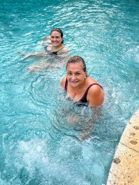 mãe e filha brasileiras na piscina - swimming swimming pool senior adult child - fotografias e filmes do acervo