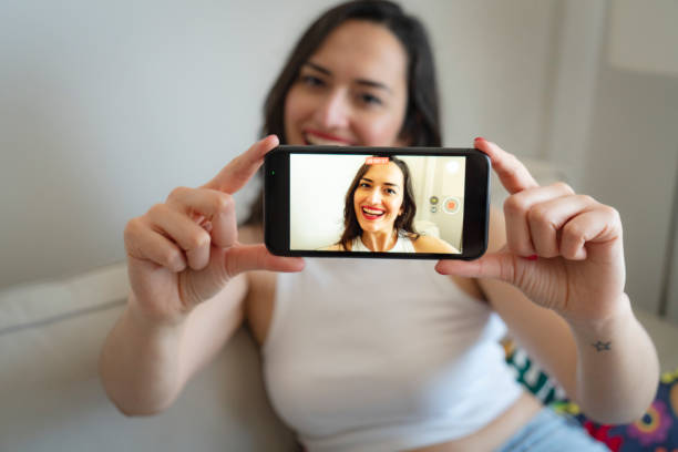 istock Woman using mobile phone recording video live streaming online at home 1904384584