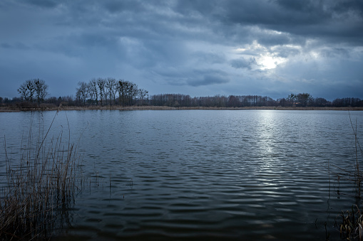 Dark evening clouds with glow from the moon over a calm lake, eastern Poland
