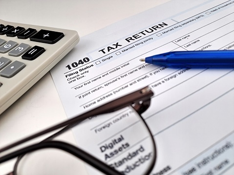 1040 Close up of a Taxes return form with calculator, ballpoint pen end glasses.