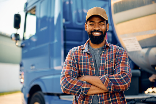 Happy African American truck driver with crossed arms looking at camera. Copy space.