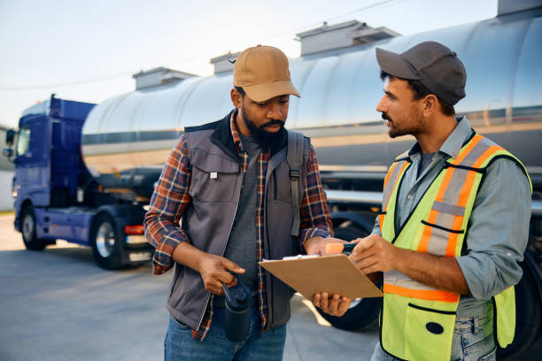 istock Freight transportation manager and black truck driver going through checklist on parking lot. 1904505786