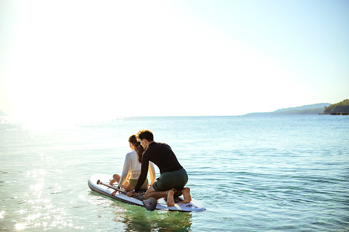 Man teaches a woman to paddle on a board at sea