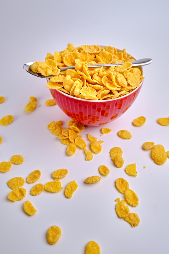 Corn flakes in a red bowl on a white background. Delicious sweet breakfast. Nutrition and health concept