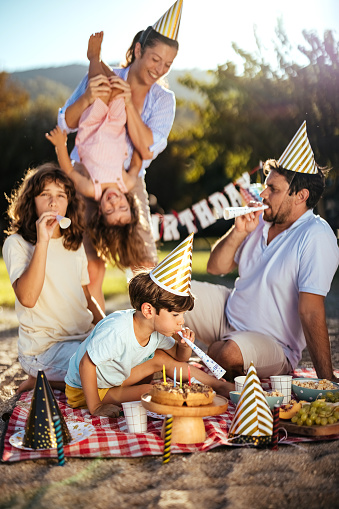 Children celebrate their birthday with their parents on the beach. A man and a woman celebrate their son's birthday on the beach.