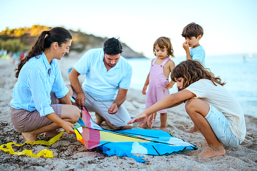 Family with three children on the beach preparing to fly a kite