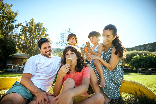 Happy family with three children sitting and eating ice cream at the sea