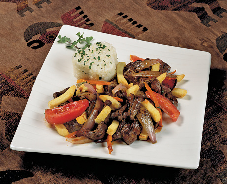 Peruvian food lomo saltado:A salted beef with tomatoes, onion, fried potatoes and rice.