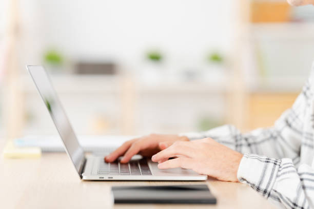 istock Hands of a man using laptop sitting at home 1904622552