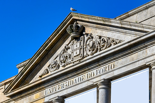 Porto, Portugal - Feb. 16, 2023: Architectural pediment with stone carvings in an ancient building of the University of Porto.