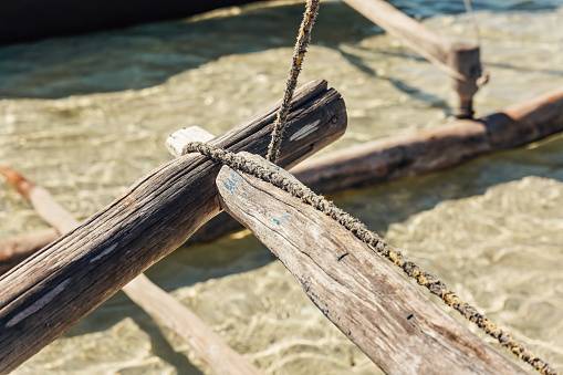 Simple natural rope tied around wooden part of pirogue - African simple fishing boat, closeup detail