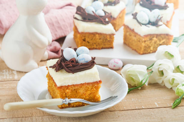 istock Easter carrot cake bars decorated with chocolate nest and chocolate candy eggs blossoming cherry or apple flowers on rustic light wooden backgrounds. Easter holiday meal. Traditional Easter food. 1904706524
