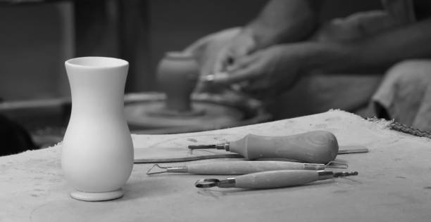istock Workshop. Art Studio. Potter at work. White Clay Vase on Table. Potter's tools. Potter's hands on a Background. Monochrome 1904711757