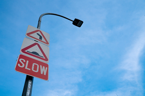 Slow down road sign on blue sky background with copy space for text or imag