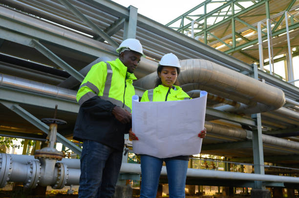 istock Male and female engineers check the drawing system inspection with the real pipe system of the new construction project, engine engineer, Sysetm cooling machine, compared to drawing design. 1904741414