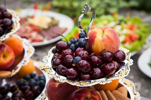 Wedding reception after wedding ceremony includes fruit, tasty, ripe, fresh peaches, cherries, blueberries and other snacks.