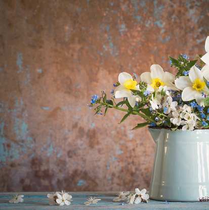 spring flowers in jug on old wooden painted background