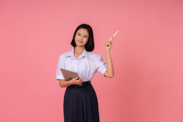 istock Asian female student presenter for world education Presenting something with a pen and holding a tablet Study at famous schools and tutoring institutes Taking photos in a pink background studio 1904809204