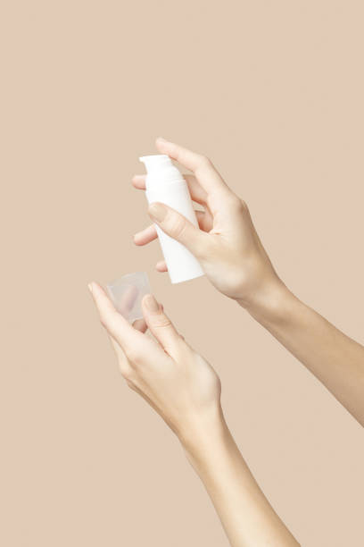 istock A womans hands holding a white cosmetic bottle on a beige background 1904811454