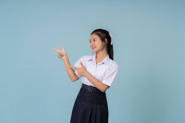 istock Asian female high school student posts a presentation for use on a website or poster. Educational presenter of Institutes and tutoring schools Taking photos in a studio with a blue background 1904825126
