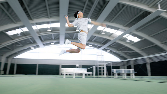 Young male tennis player scoring points in singles match on an indoor tennis court.