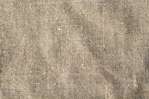 crumpled natural flaxen fabric, top view, linen textile background