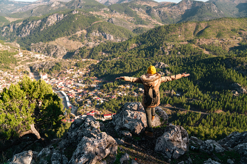 Young woman with open arms on a high hill. Freedom concept