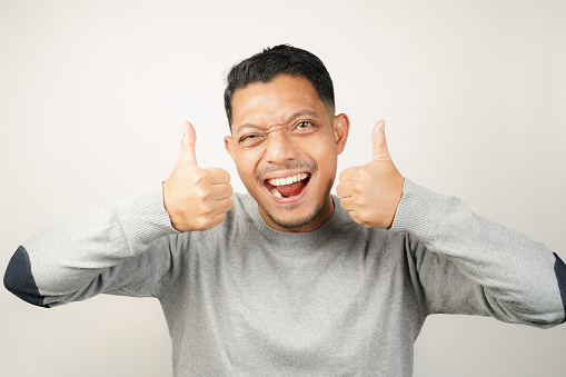 Cute happy face of handsome Asian man with thumbs up, steady expression