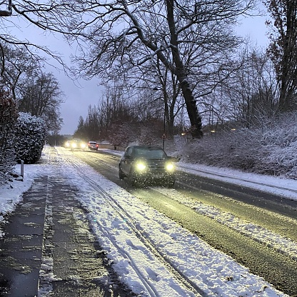 Vehicles navigating a frosty roadway on a winter morning