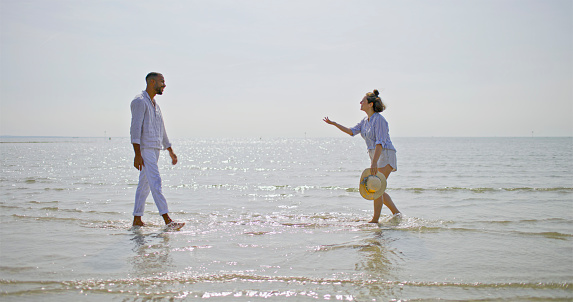 Couple running on beach during vacation in sunny day.