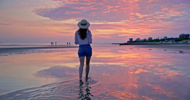 istock Woman walking in shallow water on beach 1904874246