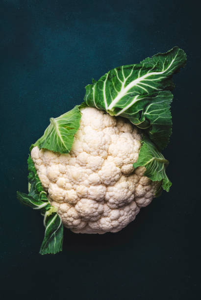 istock Fresh organic white cauliflower cabbage with leaves on old rustic green table background, top view 1904877145