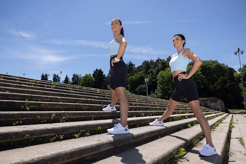 Two young athlete women doing some syncro exercises in the park on full sunny days.