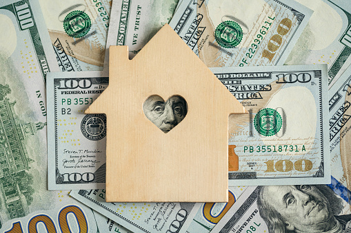Wooden house model on background of US dollars banknotes. Housing market, purchase or rental of real estate. The concept of buying and selling real estate.