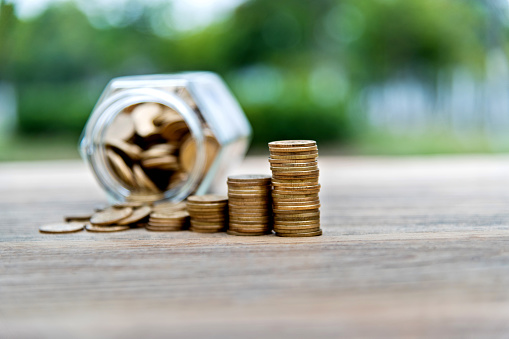 Coin stairs and jar on wooden table.