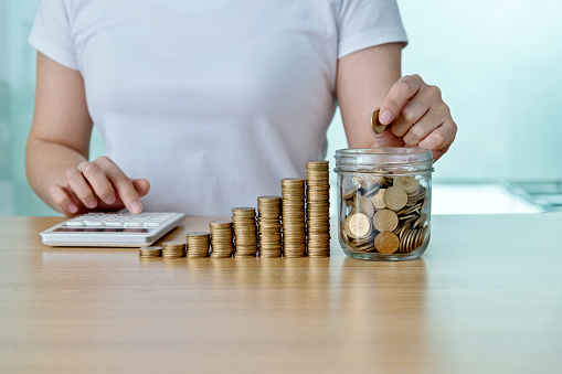 Woman counting coins with calculator.