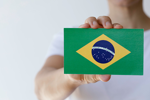 Hand is showing Brazilian flag to camera.