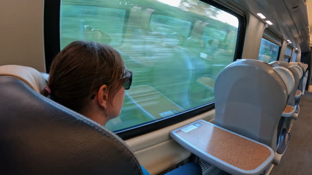 Young woman solo traveller sitting by the window on a train ride across England