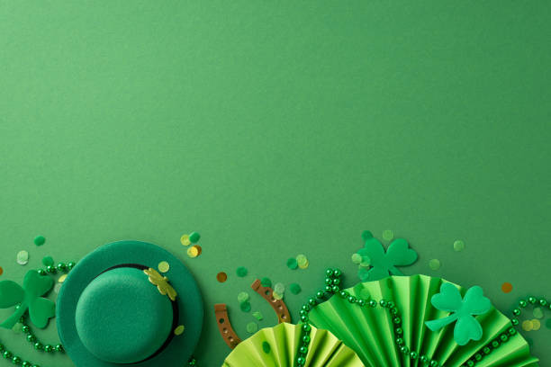 istock Experience Saint Patrick's Day joy through this top-view arrangement: leprechaun's hat, lucky horseshoe, animated fans, shamrocks, confetti, beads on green canvas. Utilize spacious background for text 1904963126