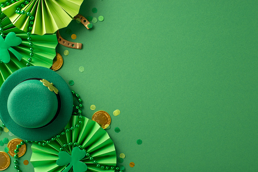 Vibrant Saint Patrick's Day setup: top view leprechaun's hat, lucky horseshoe, coins, animated fans, shamrocks, confetti, beads arranged on lively green background, providing open canvas for message