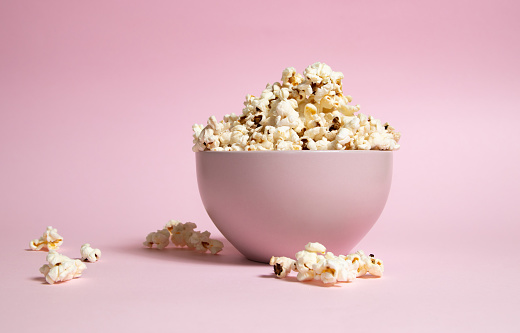 Popcorn in a pink bowl over pink background